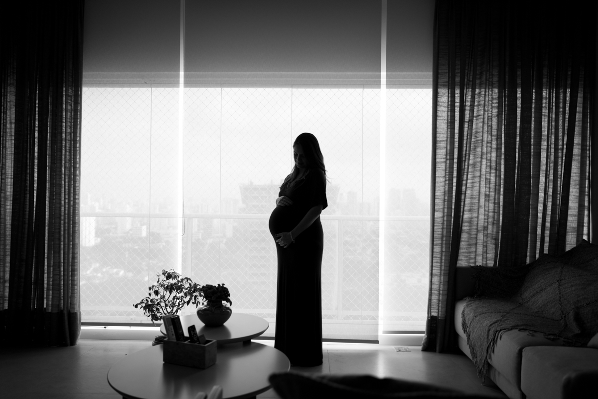 gestante em foto contra-luz na janela da sua casa em SP