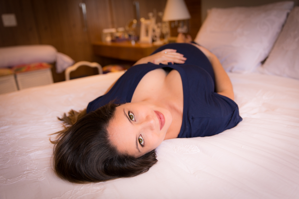 gestante admirando sua barriga de 9 meses em foto feita em sua casa em SP