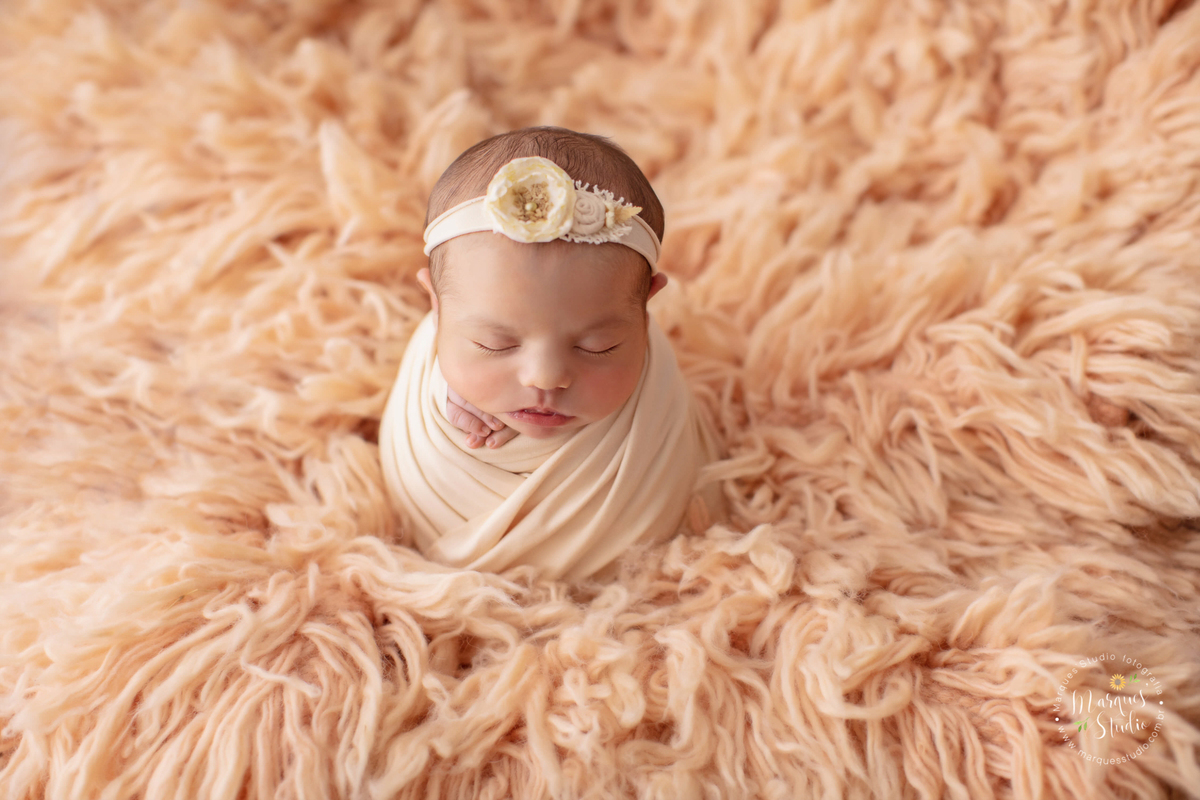 Foto tirada no ensaio newborn em studio localizado na Zona Oeste de São Paulo, SP. Na foto a bebê Laura está enrolada em um wrap salmão em cima de um tapete também salmão