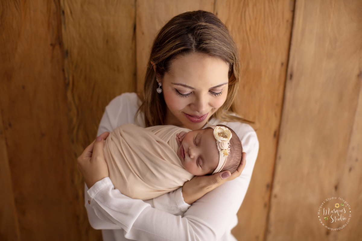 Fotografia tirada no ensaio newborn da Laura de 11 dias. Na foto a bebê está enrolada em um wrap salmão e está no colo da sua mamãe que dá um cheirinho nela. O studio encontra-se localizado na Pompeia - São Paulo, SP