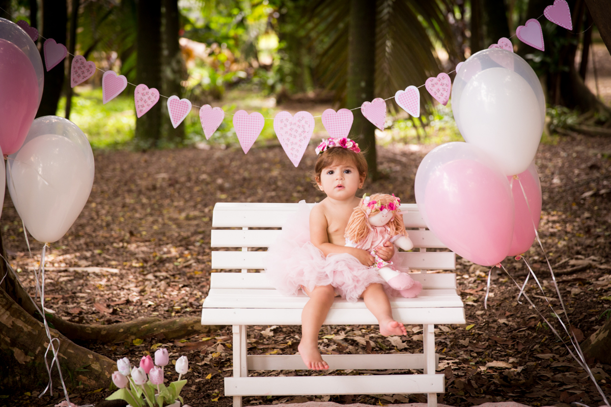 menina segurando sua boneca sentada no banco com bexigas