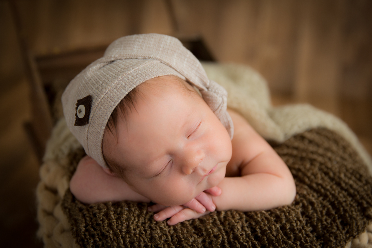 foto de recém nascido no puff com rouquinha e mãozinha no queixo feita no Marques Studio em SP