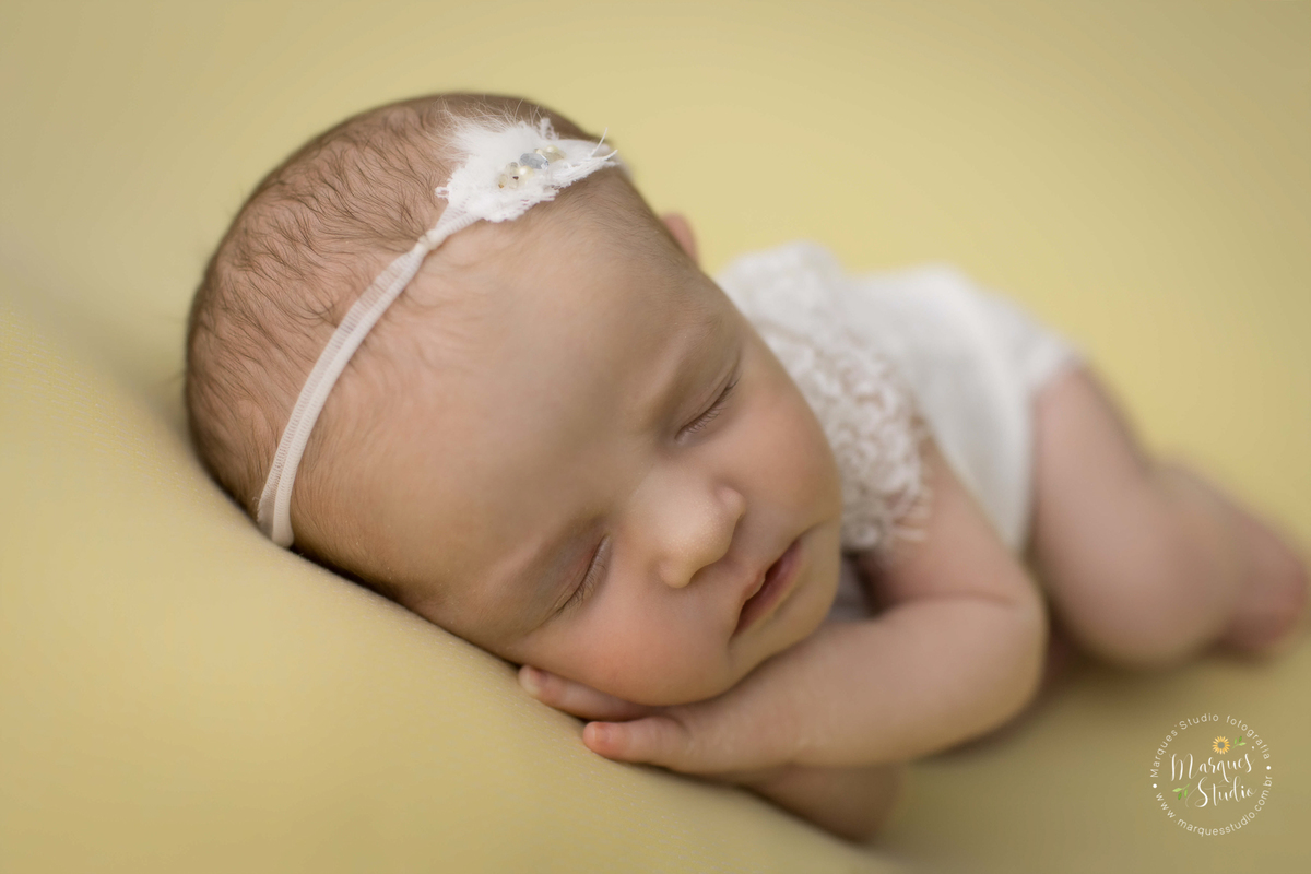 Foto feita no ensaio newborn da Laura de 14 dias. Na foto a bebê está deitada em um puff amarelo com os dois braços embaixo do queixo, usando roupinha branco. Studio fica localizado no Morumbi - São Paulo, SP. 