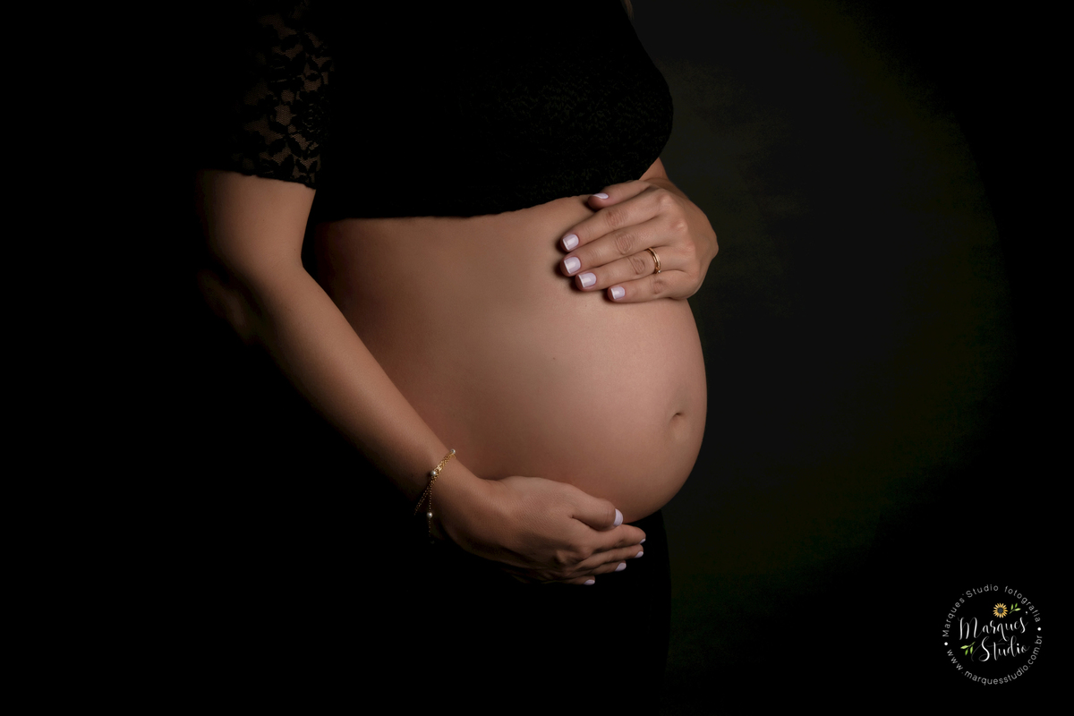 Ensaio de gestante realizado em studio localizado em Perdizes - São Paulo, SP. Na foto temos um close do barrigão de gestante da Graziella em um fundo infinito preto.