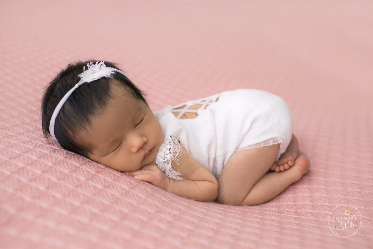 Newborn da Beatriz de 15 dias realizado em studio localizado na Vila Madalena - São Paulo, SP. Na foto a bebê está deitada em um puff rosa usando uma roupinha branca. 