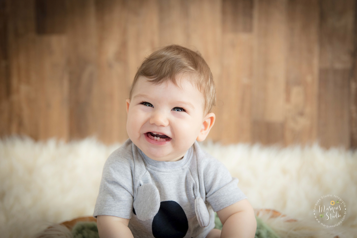 Foto feita em ensaio de bebê do Leonardo em studio localizado na Anália Franco - São Paulo, SP. Na foto o bebê está deitado de barriga pra baixo, em um tapete bege usando um blusa de bichinho, a foto foi tirada em um semi close.