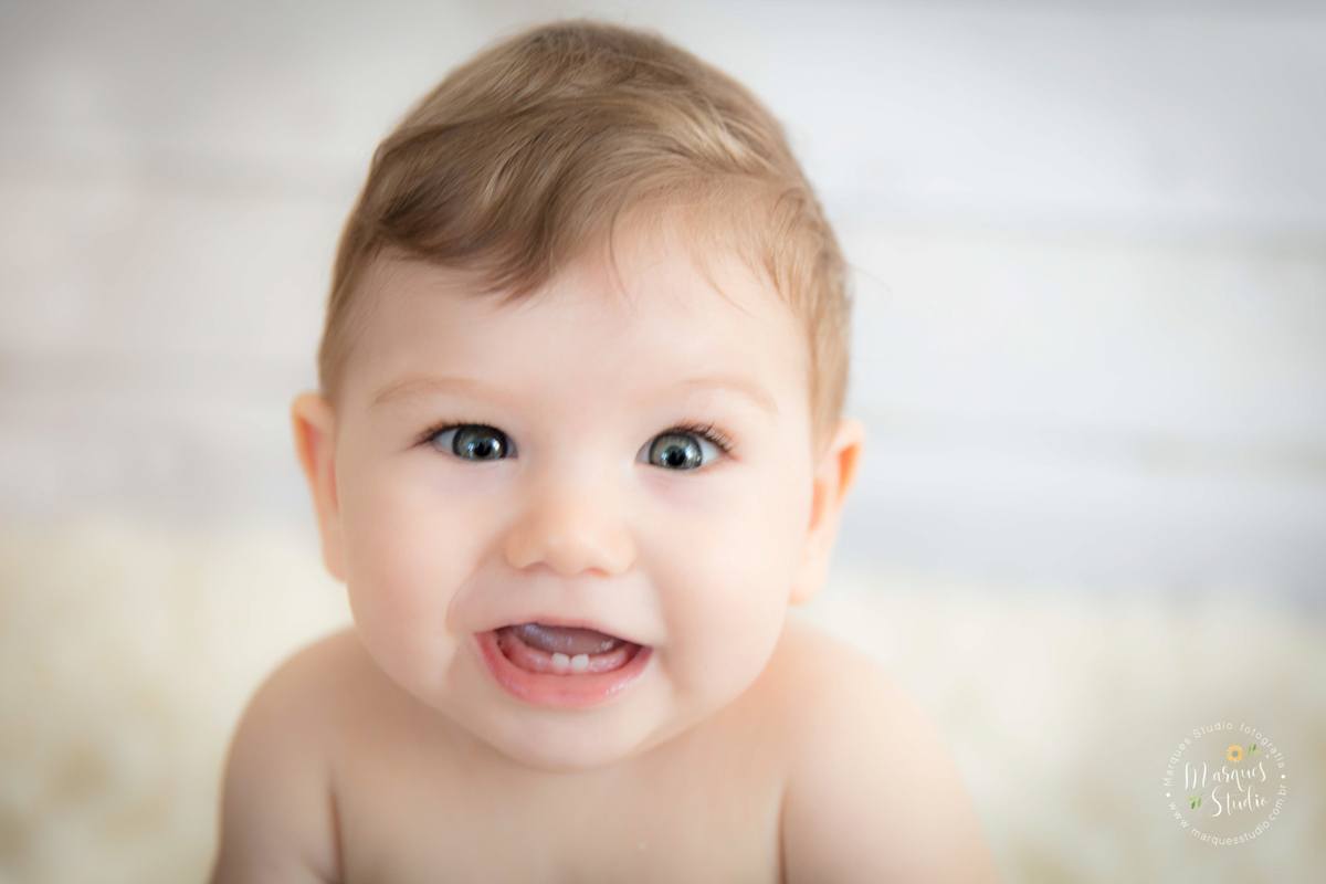 Foto feita em ensaio de bebê do Leonardo em studio localizado no Morumbi - São Paulo, SP. Na foto o bebê está sentado em um balde azul com forro azul escuro, ele está pedalinho,  a foto é um lindo close do rosto e o bebê está sorrindo.