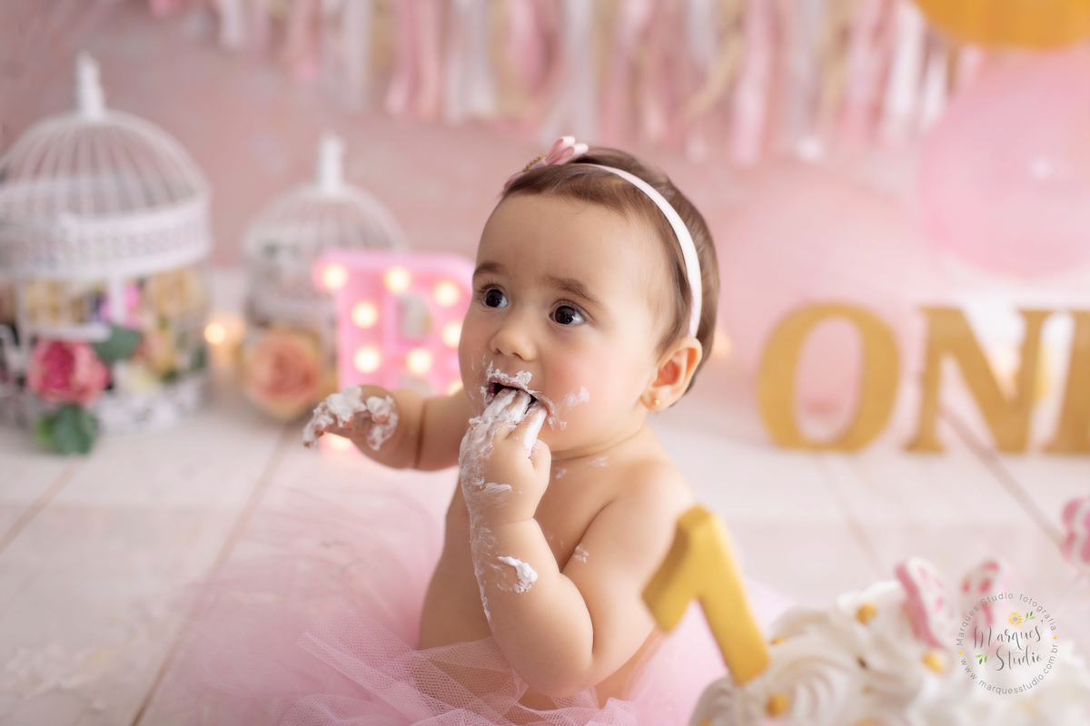 Ensaio Smash the cake da Bia de um ano. Na foto temos a Bia comendo bolo com as mãos bem sujas. O studio fica localizado em Osasco - São Paulo, SP. 