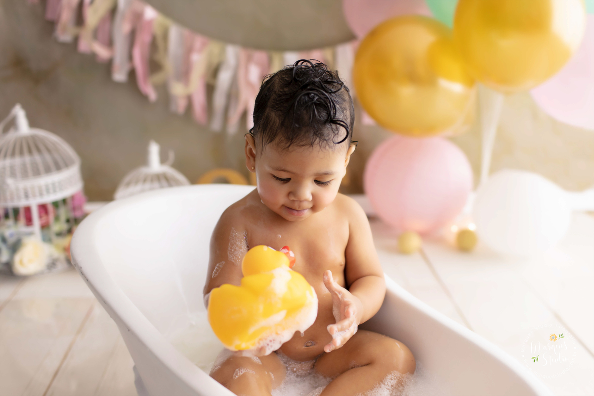 Foto feita em studio localizado em Sumaré - São Paulo, SP, na foto temos a Marina no seu smash the cake, dentro de uma banheira cheia de espuma e muitos patinhos, ela está brincando na água.