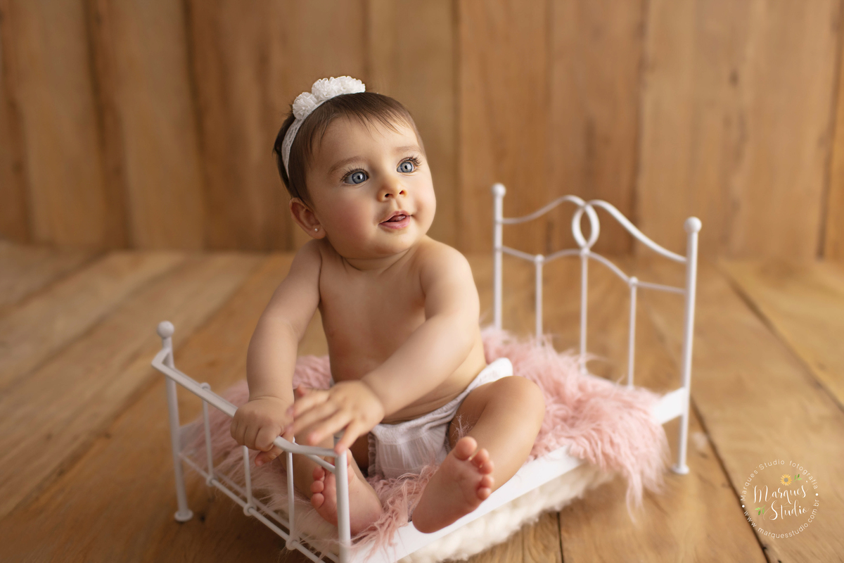 Ensaio da Giovanna de 7 meses, feito em studio localizado na Vila Leopoldina - São Paulo, SP. Na foto a Giovanna está sentada em uma caminha branco, usando uma calcinha branca e ela está dando um lindo sorriso