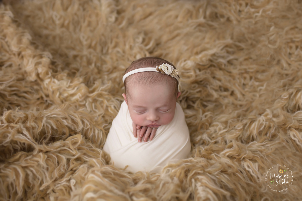 Fotografia feita em studio localizado na Av. Consolação - São Paulo, SP. Na foto a bebê está enrolada em um wrep branco em cima de um tapete mesclado.