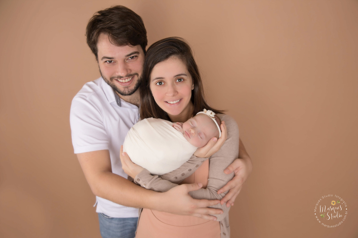 Foto de família feita no ensaio Newborn da Sophia. Na foto a mamãe está segurando a Isabel no colo enquanto o papai abraça as duas. Studio encontra-se localizado no Jardins - São Paulo, SP