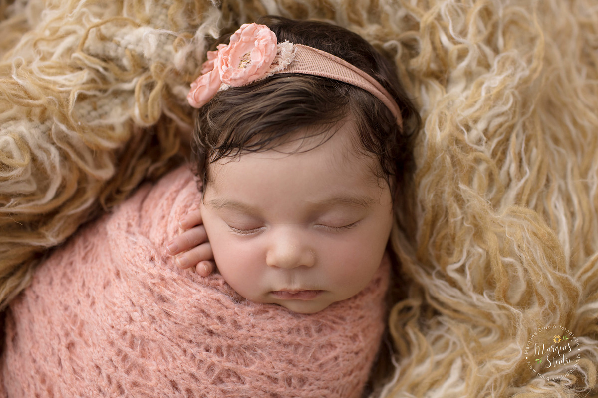 Fotografia feita em studio localizado na Av. Consolação - São Paulo, SP. Na foto a bebê está enrolada em um wrep de tricô rosa em cima de um tapete mesclado.