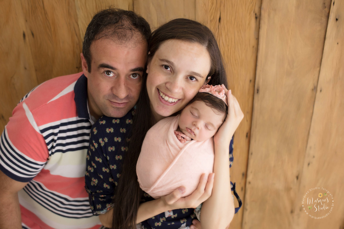 Foto de familia feita no ensaio Newborn da Isabel. Na foto a mamãe está segurando a Isabel no colo enquanto o papai abraça as duas. Studio encontra-se localizado no Jardins - São Paulo, SP