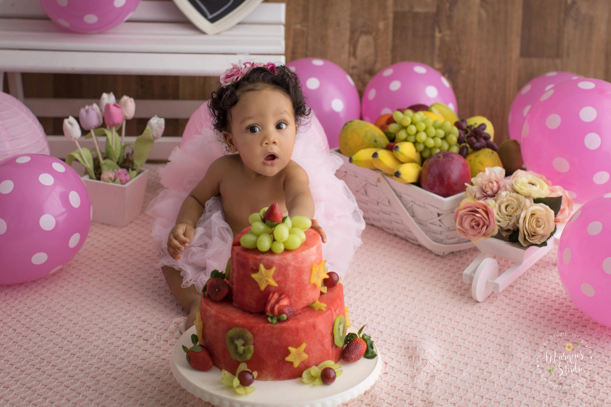 Ensaio smash the fruit feito em studio que encontra-se localizado em Santo Amaro - São Paulo, SP. Na foto a bebê Tayala está curiosa mexendo no seu bolo de frutas que é bem colorido e gostoso