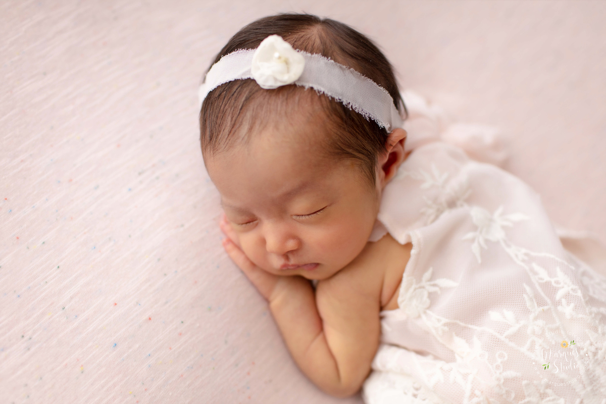 Ensaio Newborn da Sophie de 18 dias realizado em Studio localizado na Av. Consolação - São Paulo, SP. Na foto a bebê está deitada em um puff rosa, usando um vestidinho rosa e um laço na cabeça