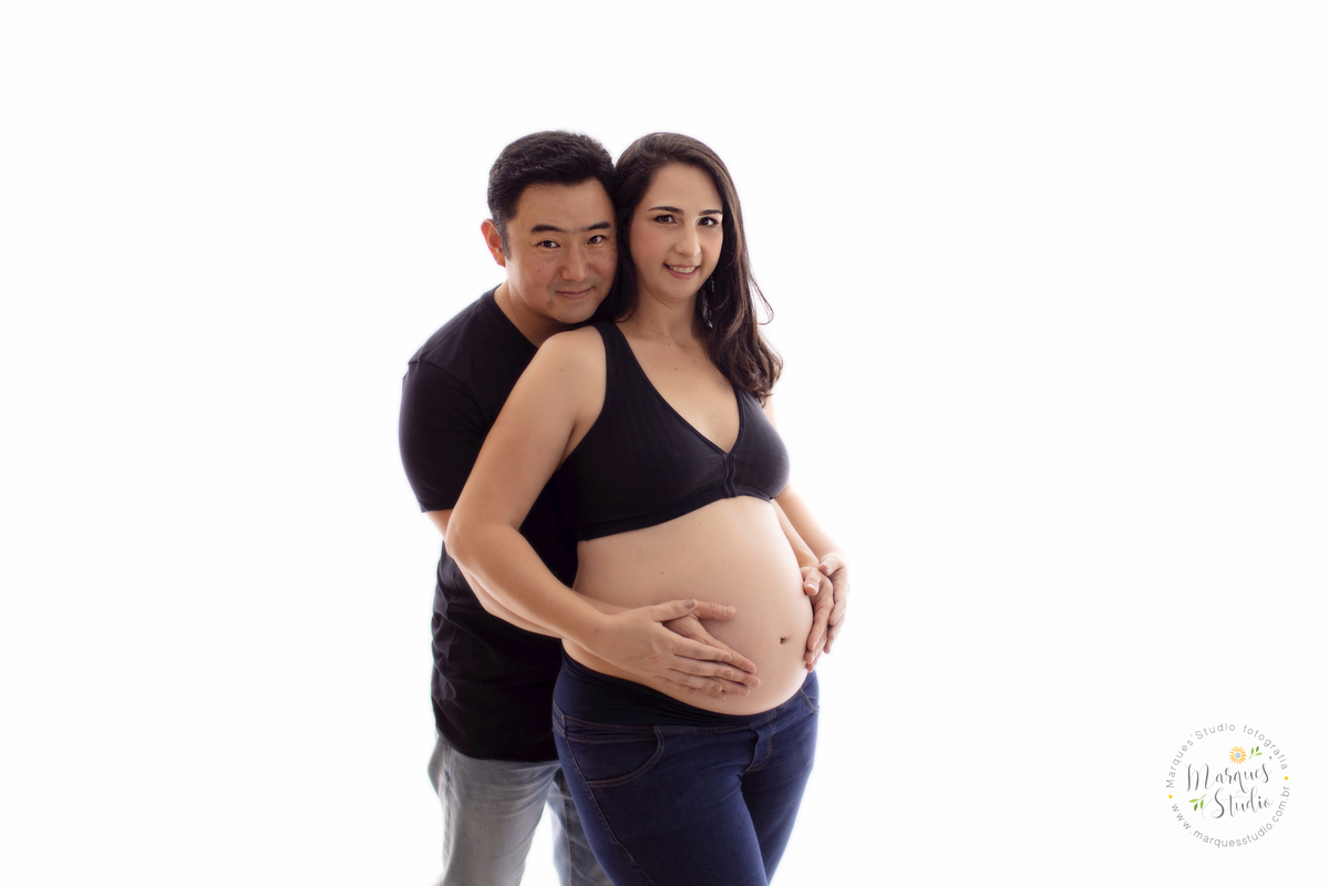 Foto feita em studio Localizado o na Vila Leopoldina - São Paulo, SP. Na foto a mamãe e o papai estão abraçados e segurando a barriga, com olhar apaixonado