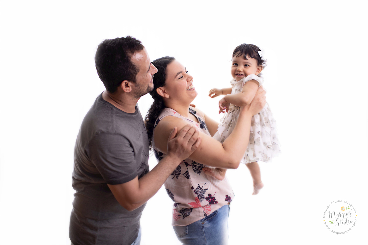 Foto de família feita no ensaio de Smash The cake da Laura de um ano em studio localizado na Av. Consolação - São Paulo, SP. Na foto a bebê está sendo jogada pra cima pelo papai e pela mamãe