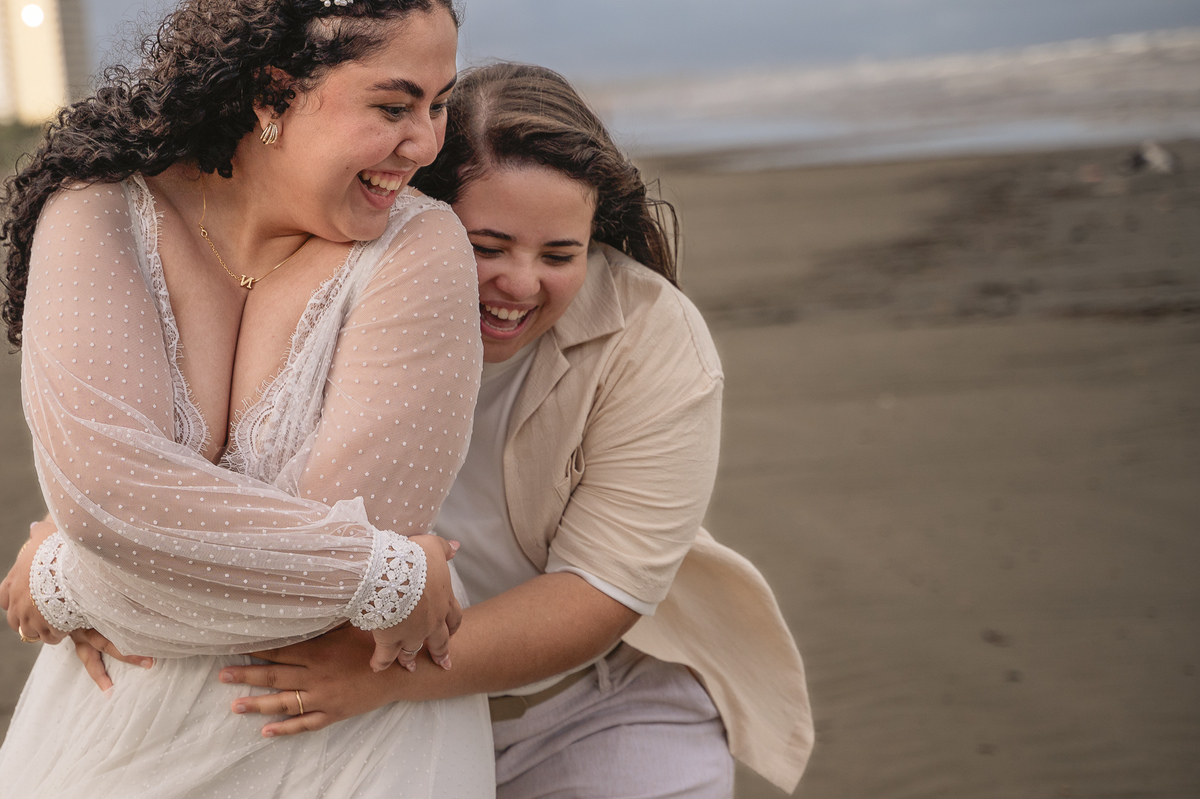 Ensaio de pré casamento na praia, casal sorridente e se abraçando