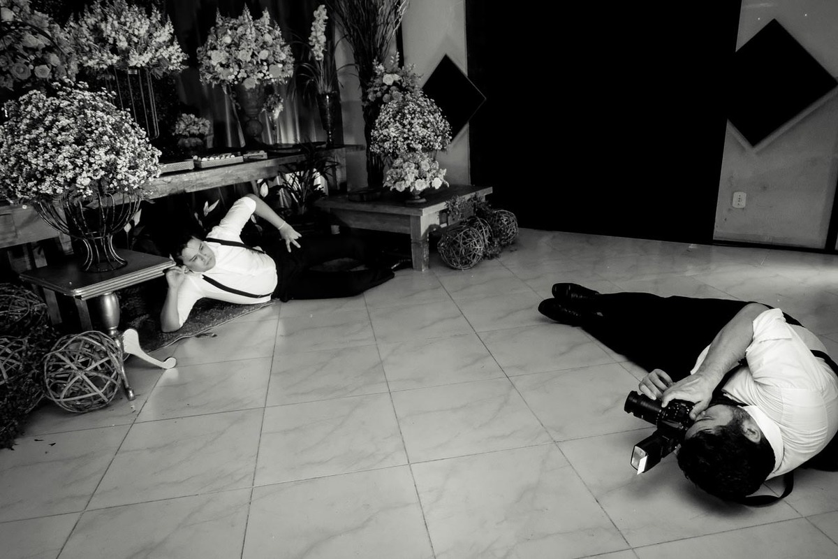 convidado com camera fotográfica deitado no chão fotografando padrinho no recanto vip em Guaratinguetá em festa de casamento foto erasmo ballot
