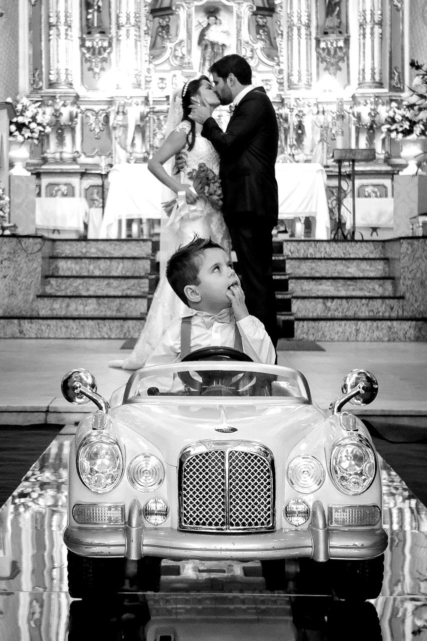 lindo beijo do casal na saída da igreja com pajem em carrinho em igreja matriz de santo antonio em casamento em guaratinguetá