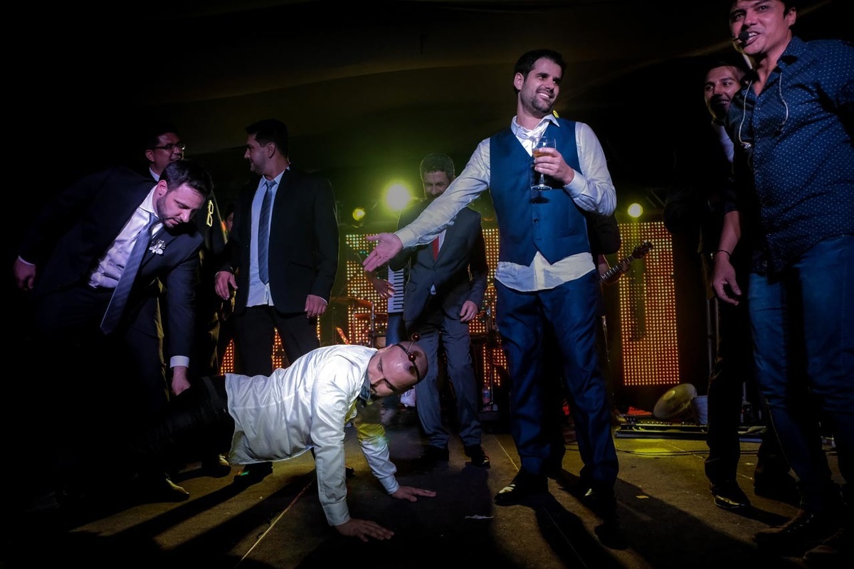 padrinho dançando até o chão em palco muito engraçado e noivo sorrindo no recanto do bosque em casamento em guaratinguetá