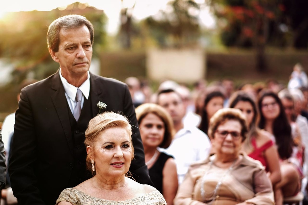 pai e mãe observam filho casamento em casamento lindo no pôr do sol no hotel fazenda sete lagos em Guaratinguetá fotos erasmo ballot