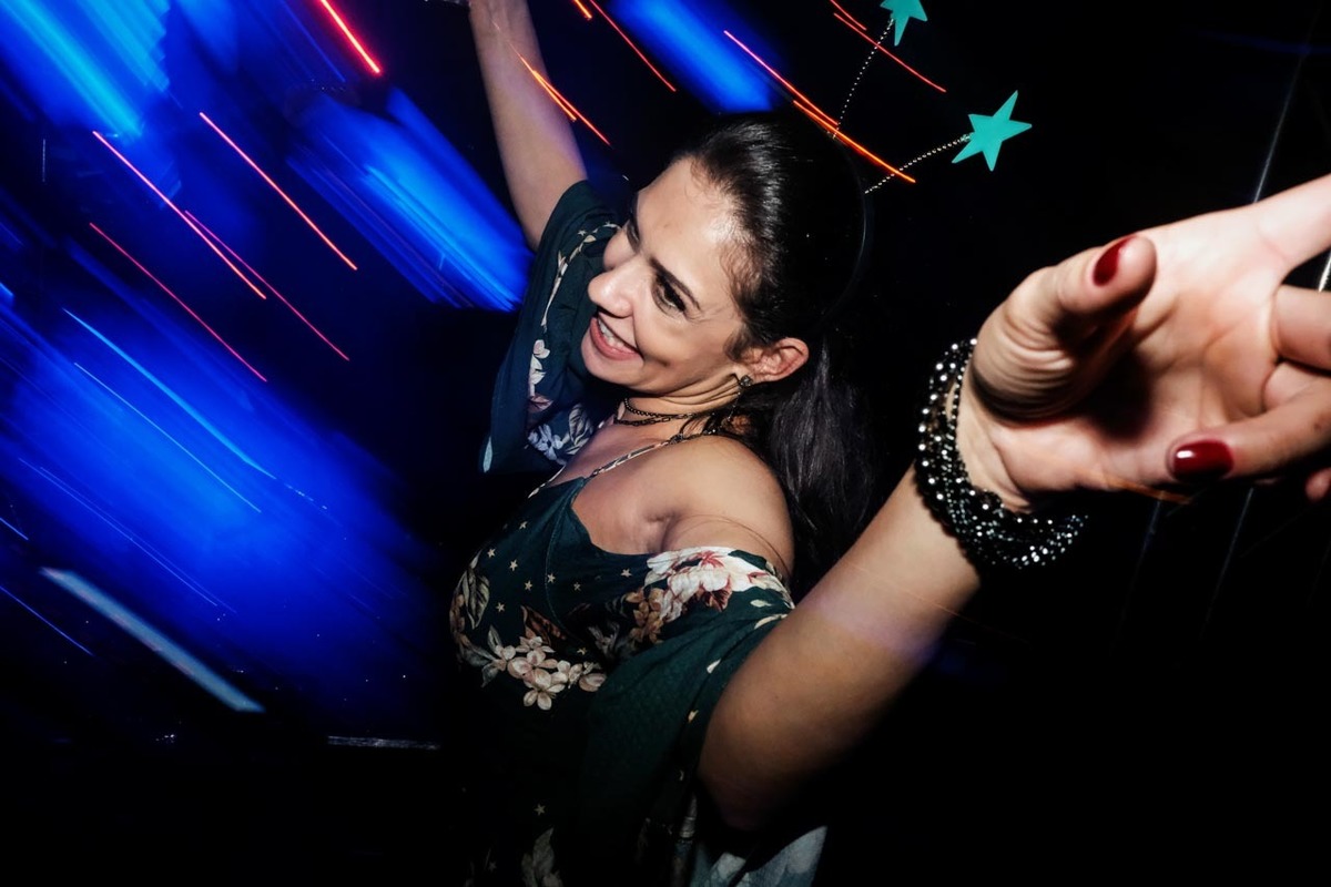 convidada dança feliz em com as músicas e luz colorida de forma contagiante em recepção de casamento lindo e animado no clube sete lagos em Guaratinguetá fotos erasmo ballot