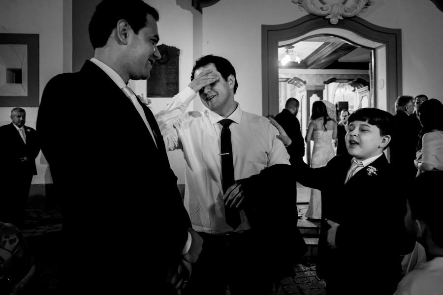 NOIVO NA PORTA DA IGREJA COM MAO NO ROSTO SORRINDO E CRIANÇA PENTELHA  EM CASAMENTO LINDO EM GUARATINGUETA