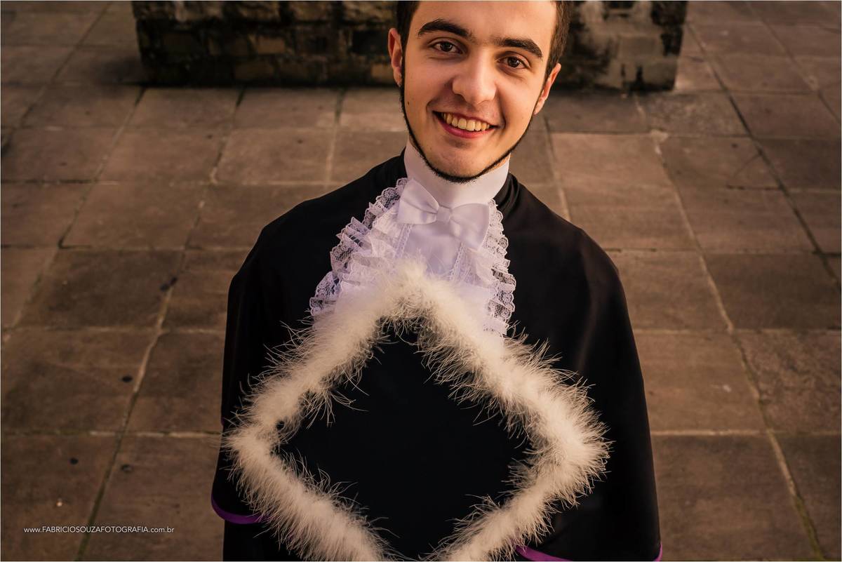 André vestido de beca segurando seu capelo por Fabrício Souza