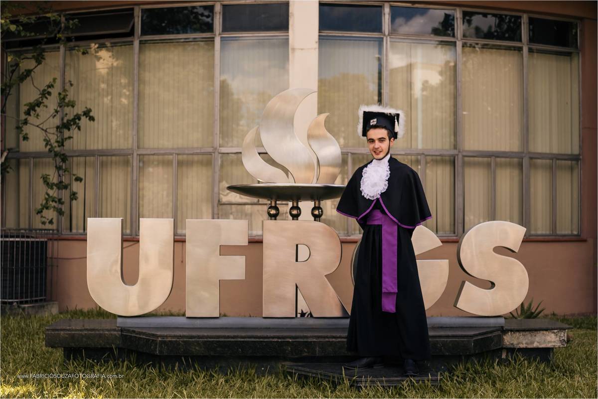 Com beca completa André na frente do letreiro da UFRGS em Porto Alegre