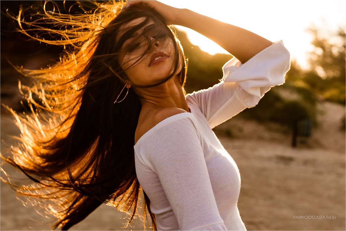izabella com os cabelos voando ao vento contornado pelo sol de um belo fim de tarde na bela praia de torres/rs no ensaio da izabella, por fabricio souza, fotografo no rs, porto alegre e região