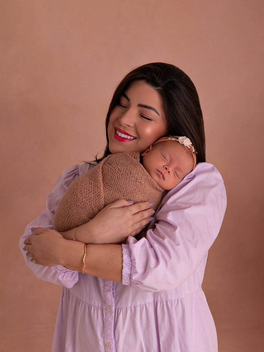 Foto de bebê recém-nascida enrolada em wrap sendo segurada pela mãe. Ensaio Newborn em Estúdio Natal/RN.