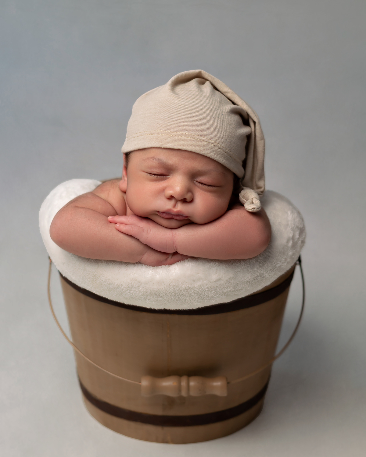 Bebê dormindo em baldinho com gorrinho em Ensaio Newborn em Natal/RN com Amoradia Foto.