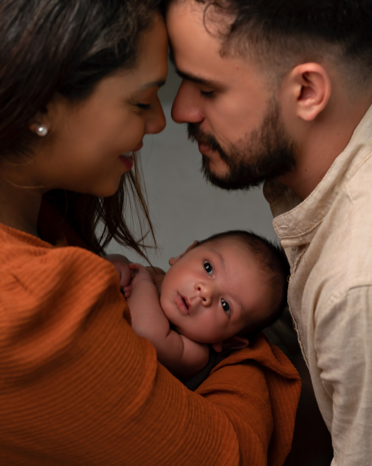 Bebê sendo segurado pelos pais em ensaio Newborn feito pela Amoradia Foto em Natal/RN.
