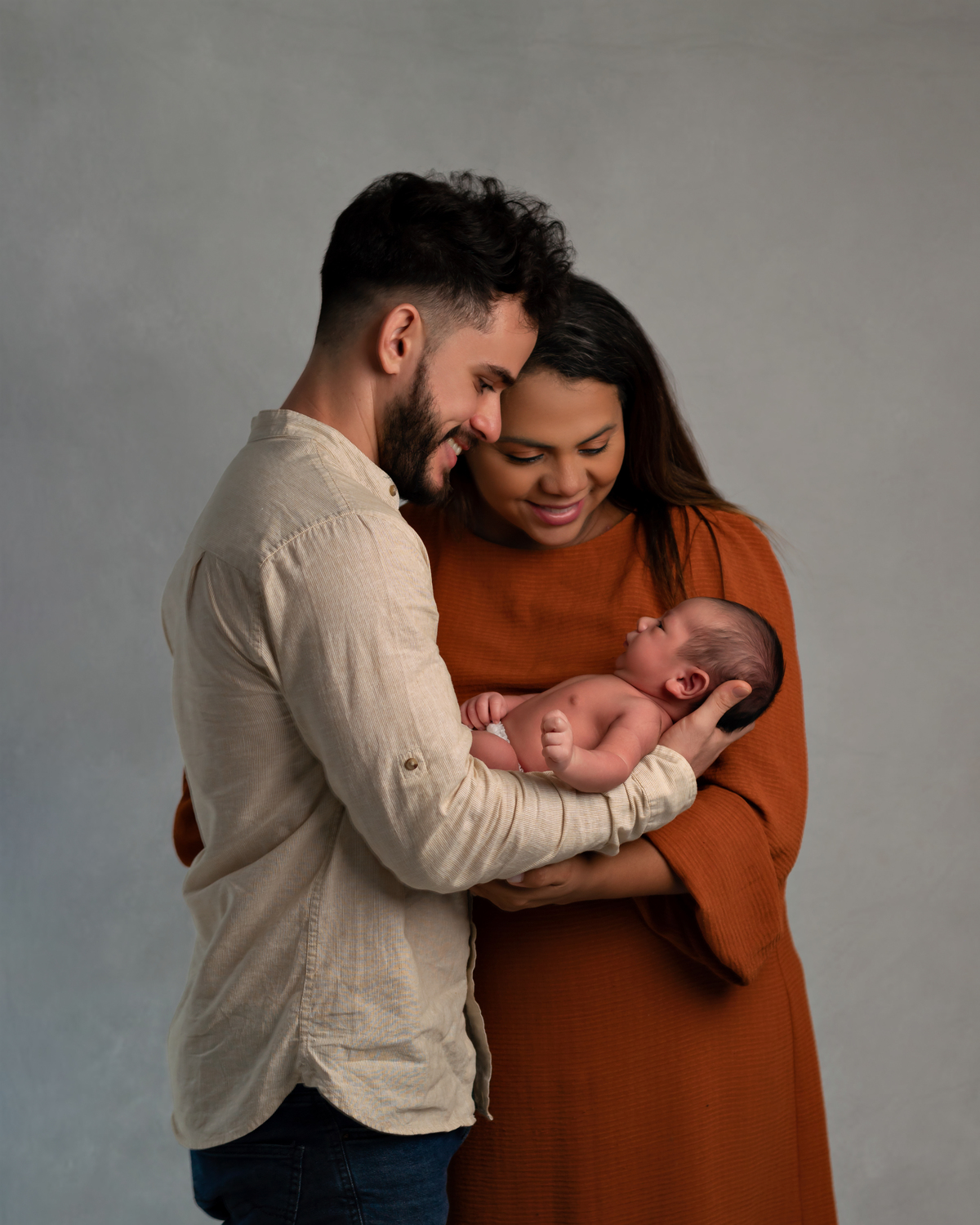 Pais segurando o bebê em Sessão Newborn. Amoradia Foto. 