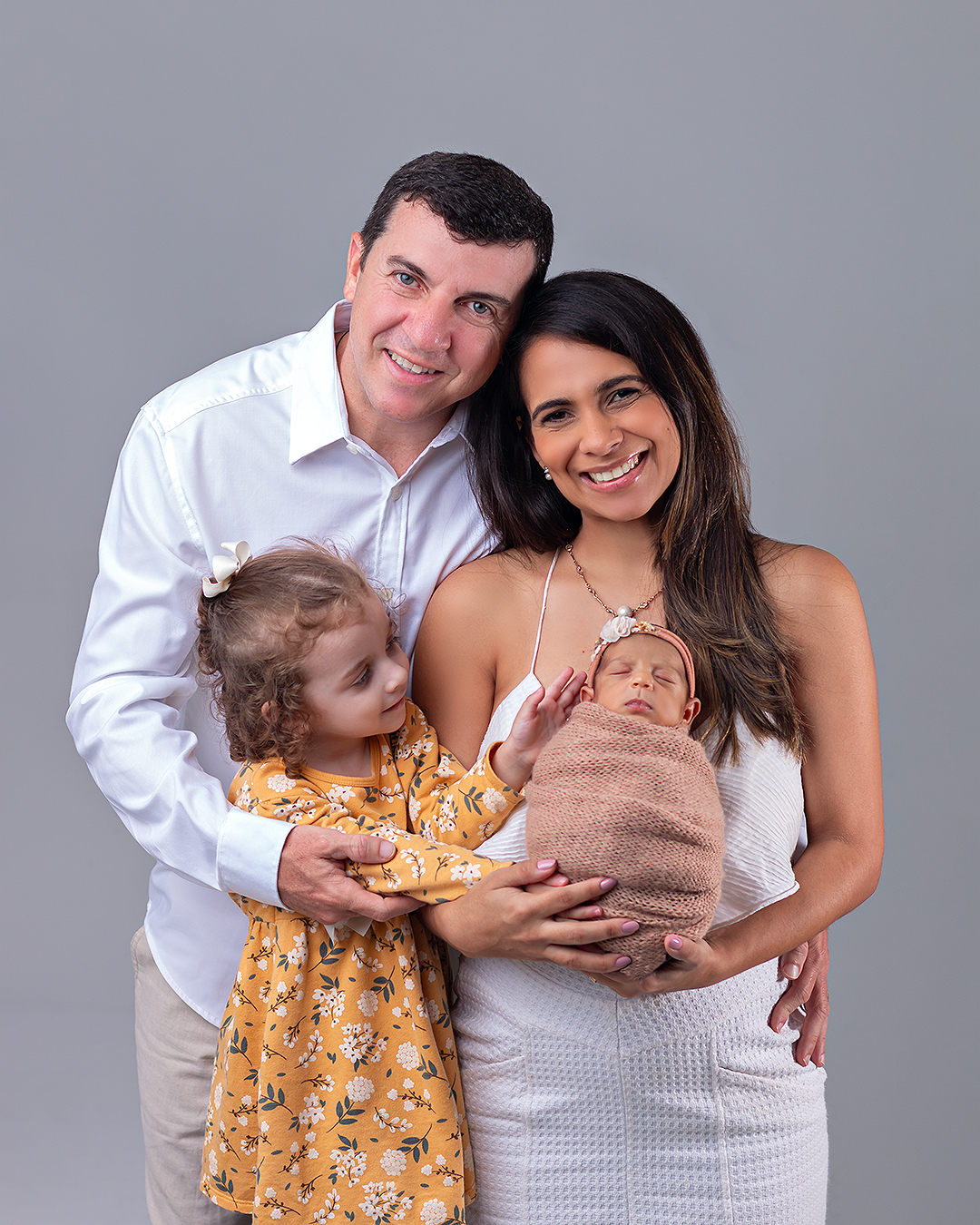 Bebê recém-nascido com os pais e a irmãzinha em ensaio Newborn