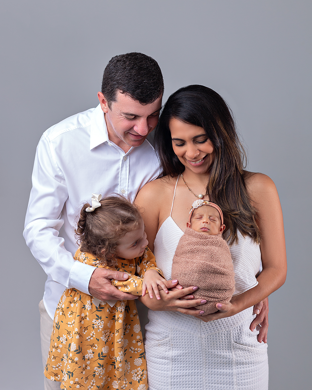 Bebê recém-nascido com os pais e a irmãzinha em ensaio Newborn