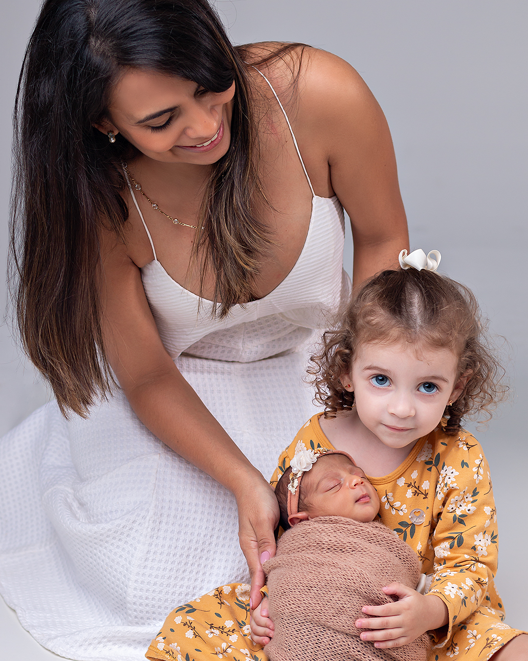 Bebê recém-nascido com a mãe e a irmãzinha em ensaio Newborn