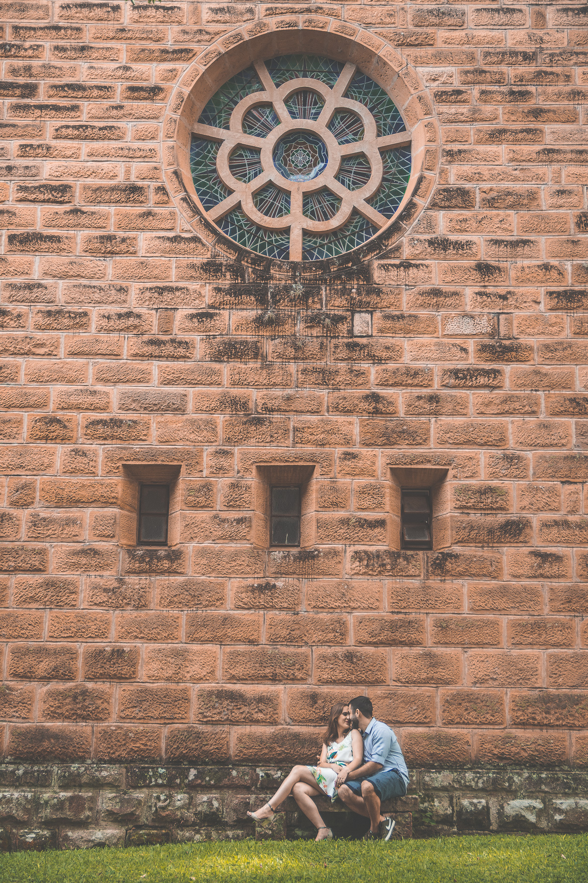 Casal sentado em banco próximo a grande parede