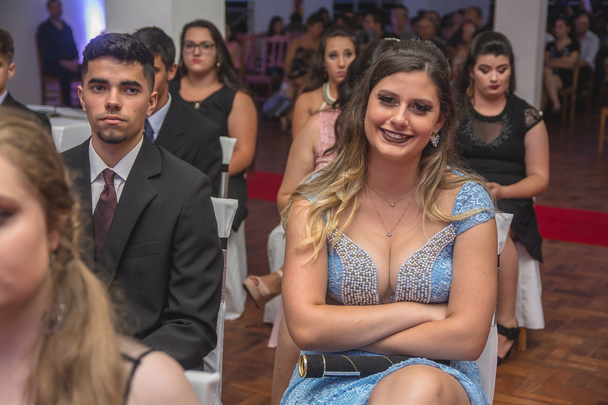 Formanda sorrindo ouvindo discurso do professor