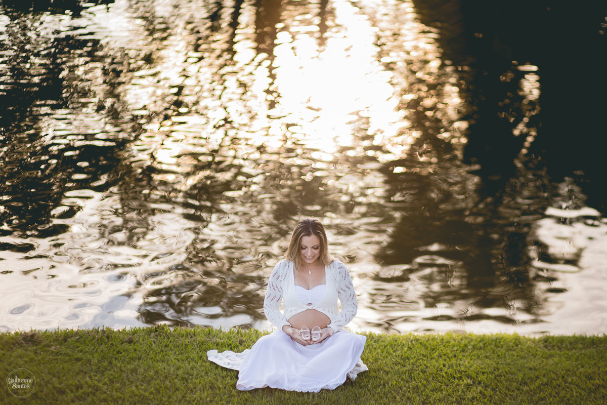 Book de Gestante por Guilherme Santos Fotografia que rolou no Hotel Fazenda Shangri-la, Brotas-SP. Sessão fotográfica no final de tarde, mãe gravida segurando um sapatinho na beira de um lago.
