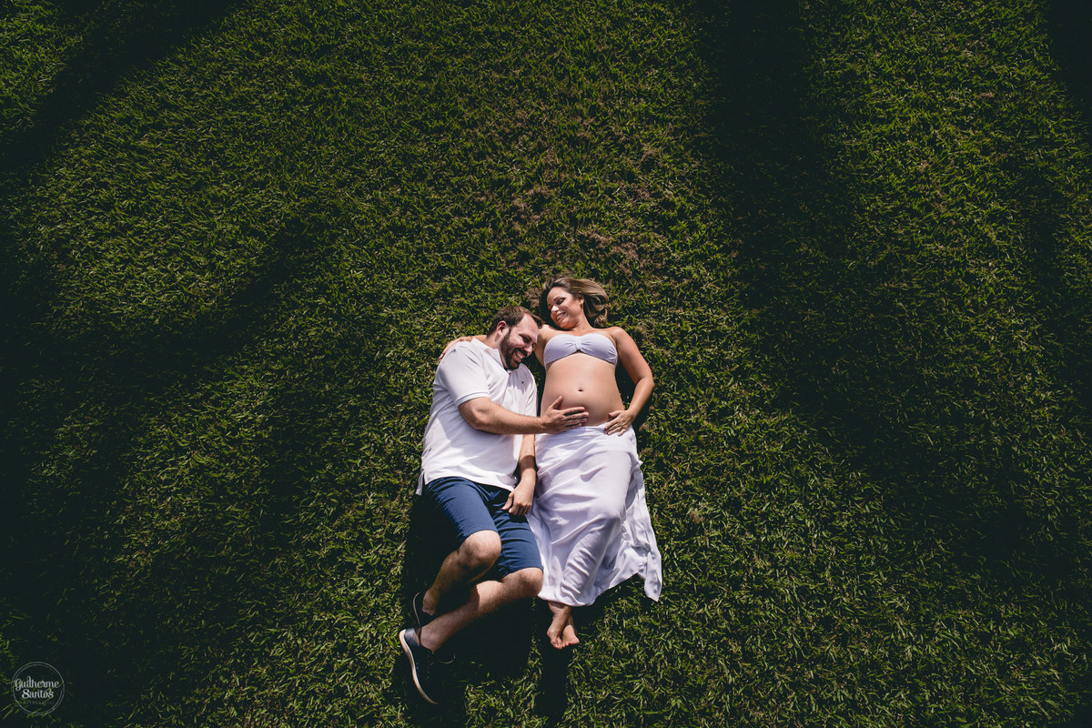 Book de Gestante por Guilherme Santos Fotografia que rolou no Hotel Fazenda Shangri-la, Brotas-SP. Sessão fotográfica no final de tarde, pai e mãe deitados juntos, segurando a barriga de gravida.