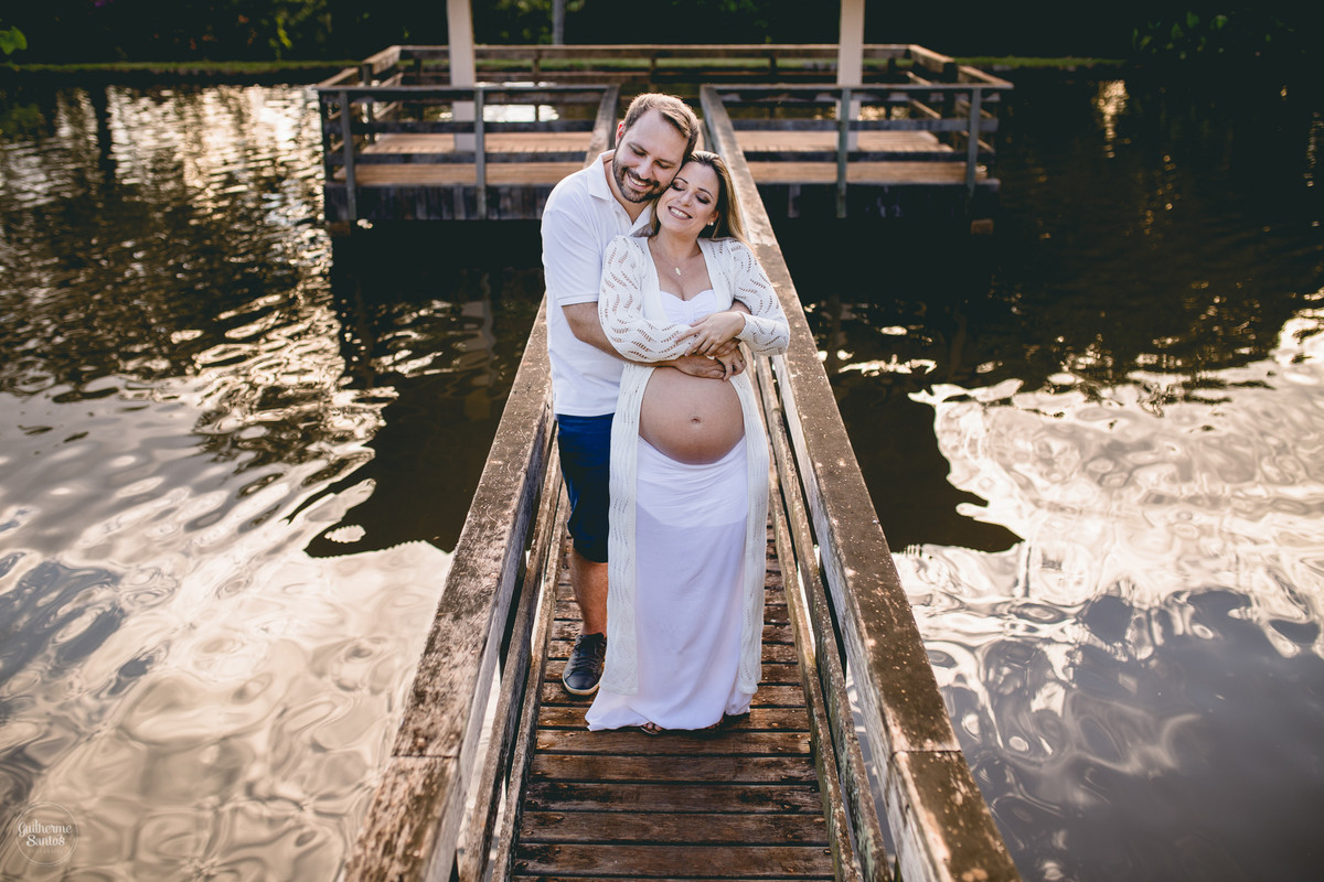 Book de Gestante por Guilherme Santos Fotografia que rolou no Hotel Fazenda Shangri-la, Brotas-SP. Sessão fotográfica no final de tarde, casal se abraçando em um deck, barrigão de gravida.