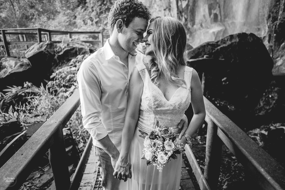 Fotografia de pré casamento feita no final de tarde pelo fotógrafo Guilherme Santos, casal de noivos de mãos dadas e se olhando, sessão de fotos na cachoeira de Brotas.