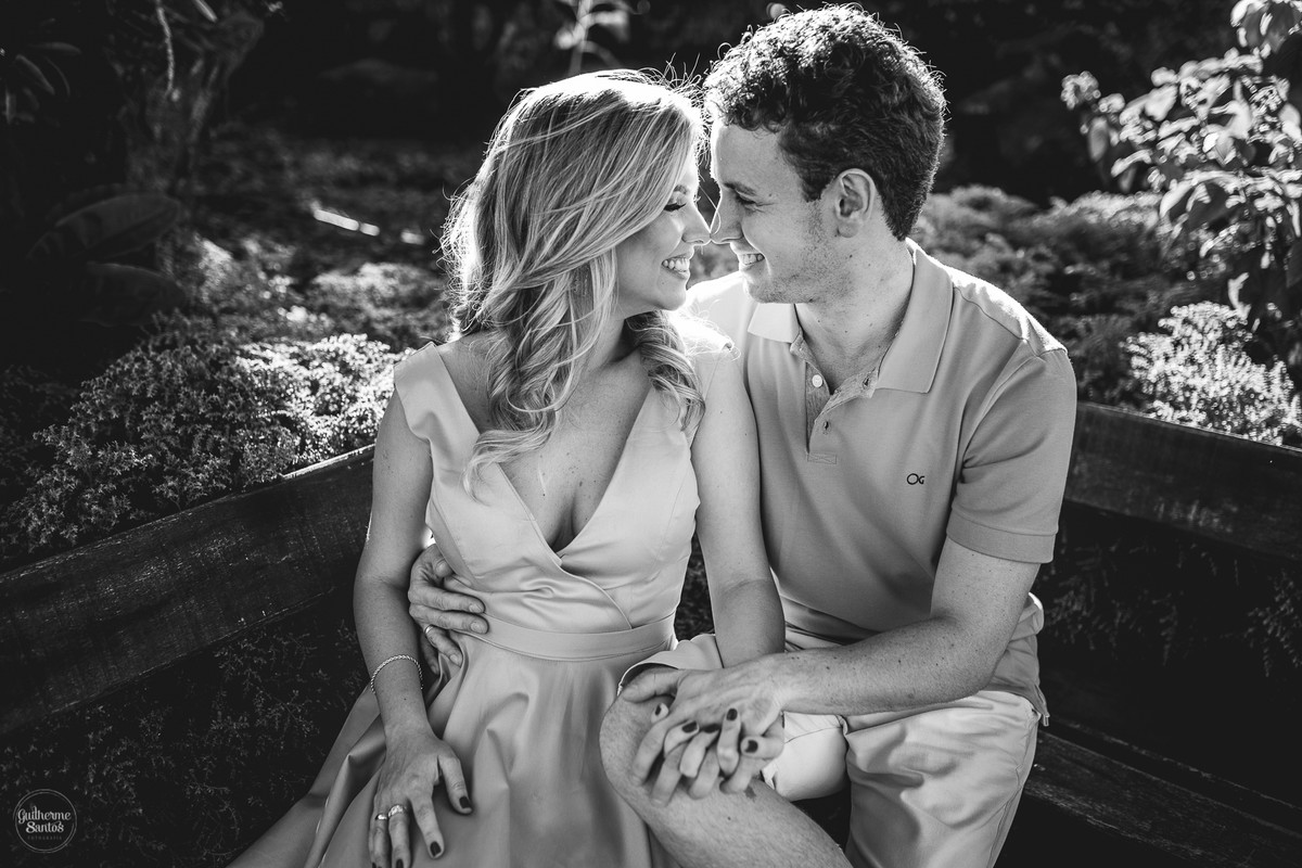 Ensaio pré casamento de Guilherme Santos Fotografia que rolou no recanto das cachoeiras em Brotas-SP, sessão fotográfica no final de tarde, casal sentado em um banco de madeira se olhando e sorrindo.