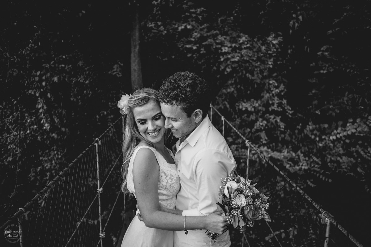 Fotografia de pré casamento feita no final de tarde pelo fotógrafo Guilherme Santos, casal de noivos se abraçando, noiva de branco na sessão de fotos segurando o buquê de flores.