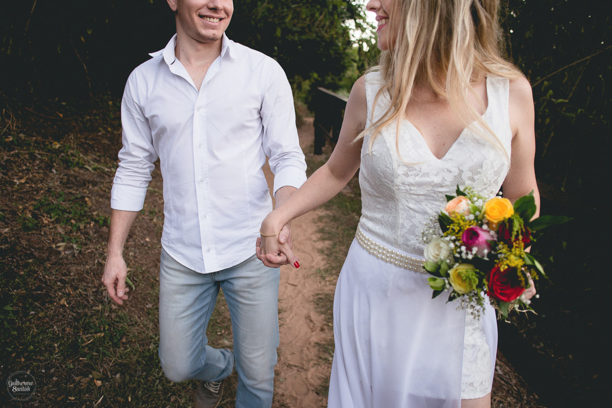 Fotografia de pré casamento feita no final de tarde pelo fotógrafo Guilherme Santos, casal de noivos caminhando no local escolhido para a sessão de fotos, sessão pré casamento em Brotas,noiva segurando o buquê de flores.