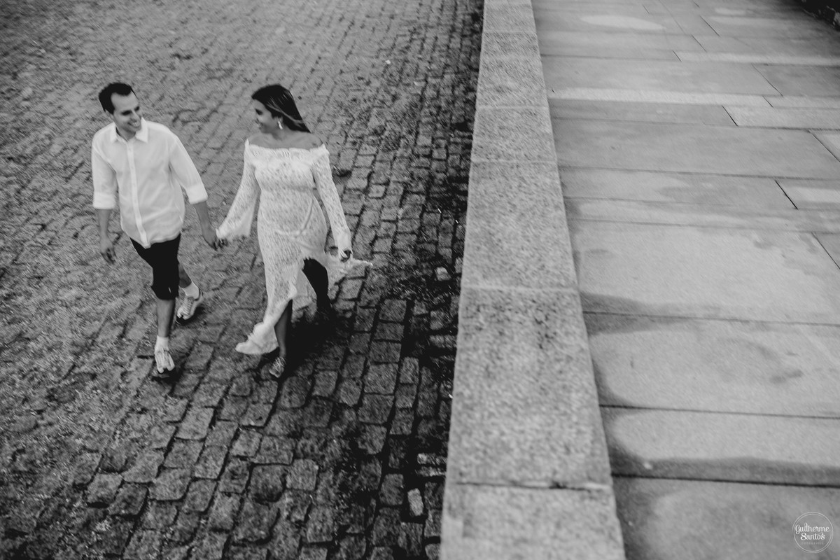 Fotografia de pré casamento pelo fotógrafo Guilherme Santos, casal caminhando no calçadão perto do mar na sessão de fotos no Rio de Janeiro.