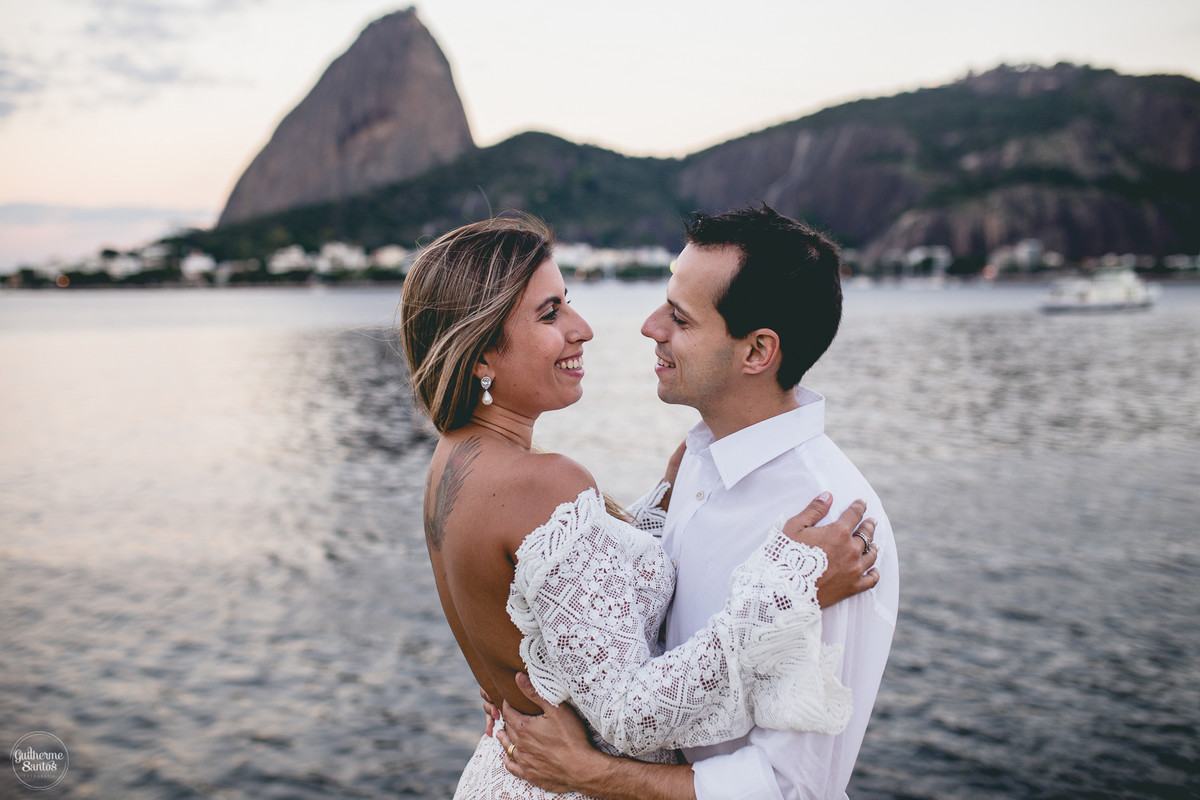 Fotografia de pré casamento pelo fotógrafo Guilherme Santos, casal se olhando, noiva com tatuagem, vista da sessão de fotos para o pão de açúcar no Rio de Janeiro.